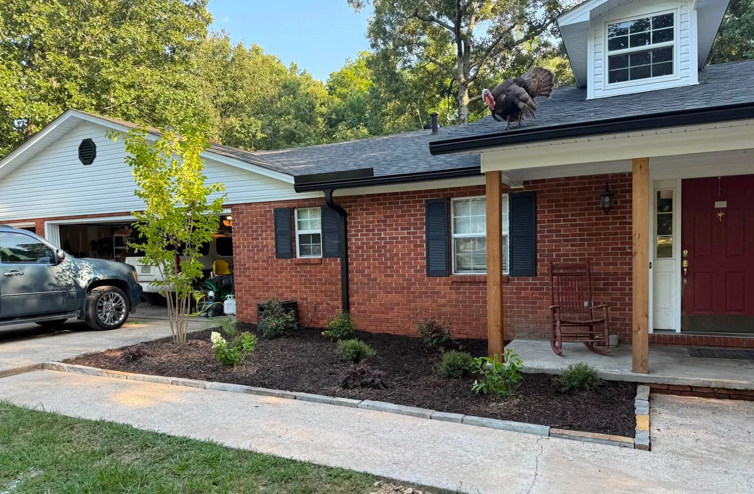 The same home with new mulch beds, shrubs, and small trees along the porch