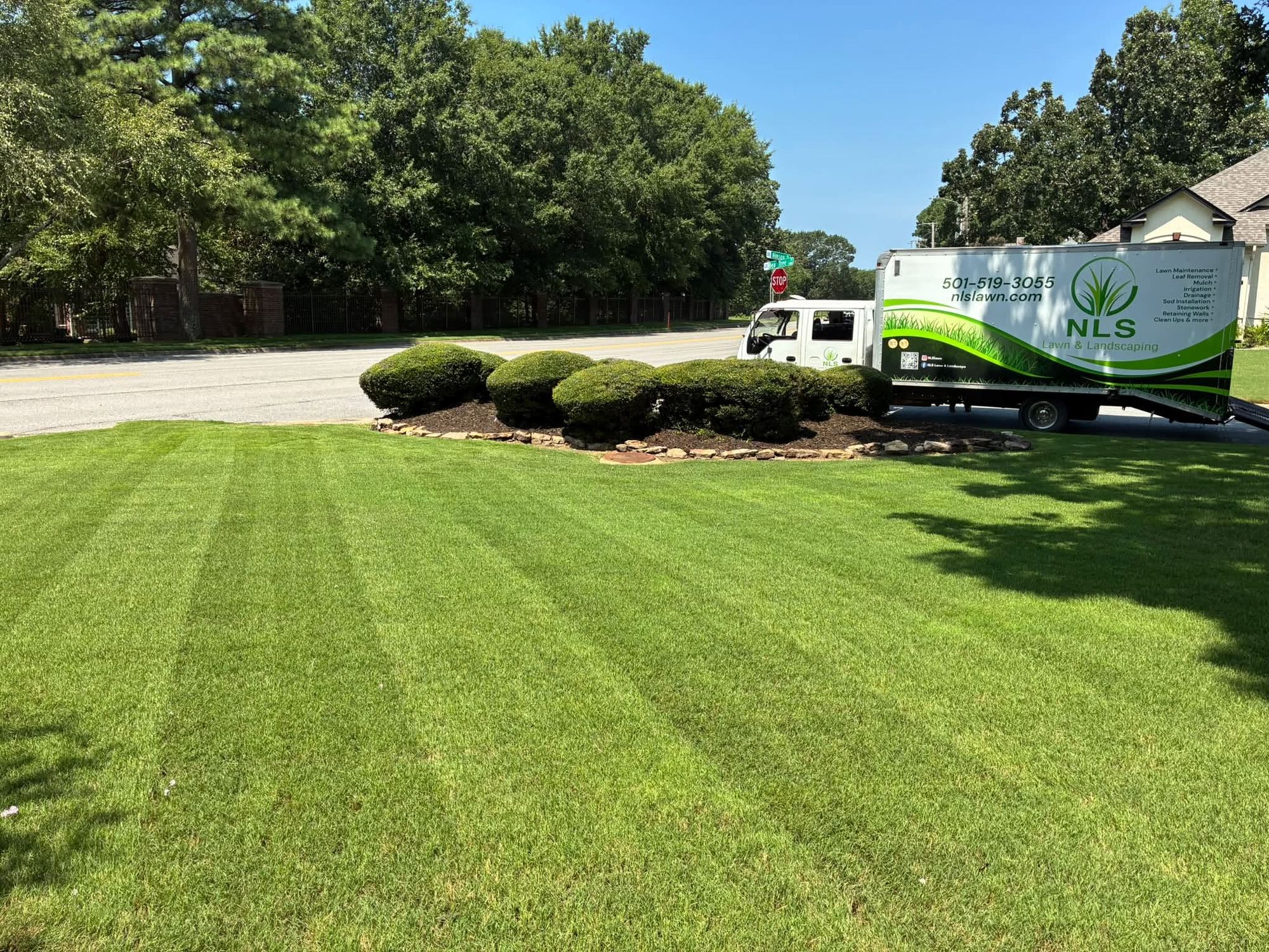 Freshly striped front lawn with the NLS Lawn and Landscape truck parked at the curb